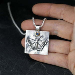 Morning cloak butterfly pendant • sterling silver with 18k gold pendant set with a dark blue sapphire