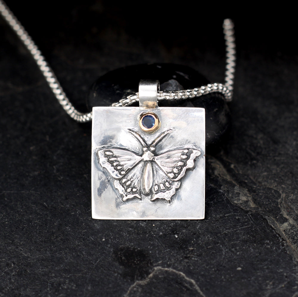 Morning cloak butterfly pendant • sterling silver with 18k gold pendant set with a dark blue sapphire